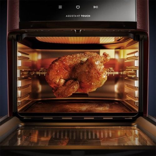 Função espeto giratório da Air Fryer Oven Electrolux Experience EAF90 vermelha, mostrando um frango inteiro assando e dourando uniformemente dentro do aparelho.